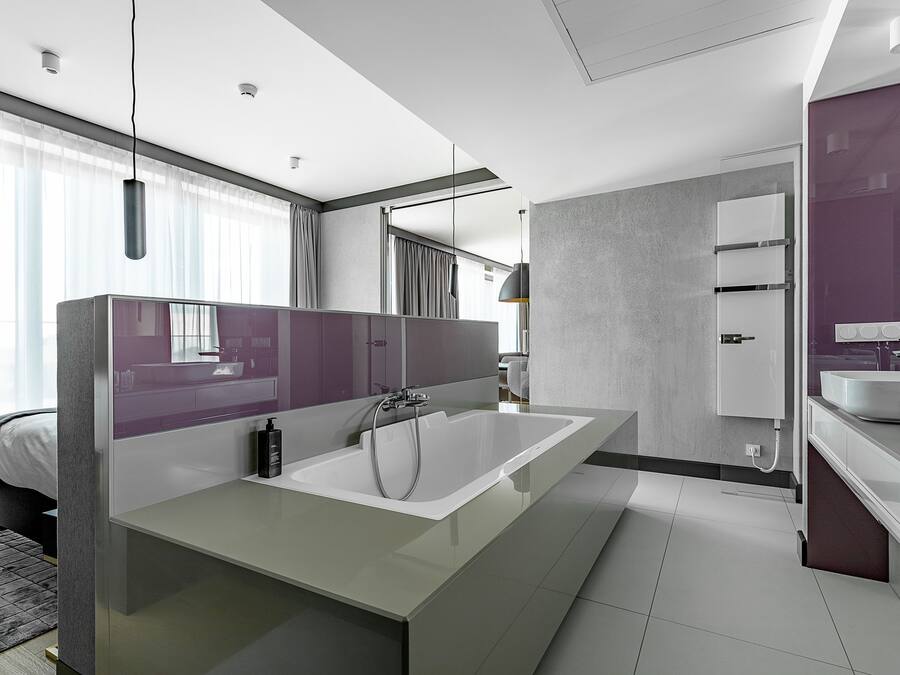 A modern bathroom with a large bathtub, a vanity with a mirror, and a separate sink area.