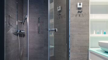 A modern bathroom with a glass shower enclosure, a white toilet, and a vanity with a large mirror and a sink.