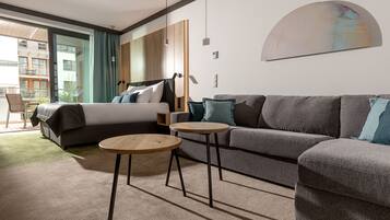 Ein modernes Hotelzimmer mit einem Bett, einer Couch, zwei kleinen Tischen und einem großen Fenster mit Blick auf die Stadt.