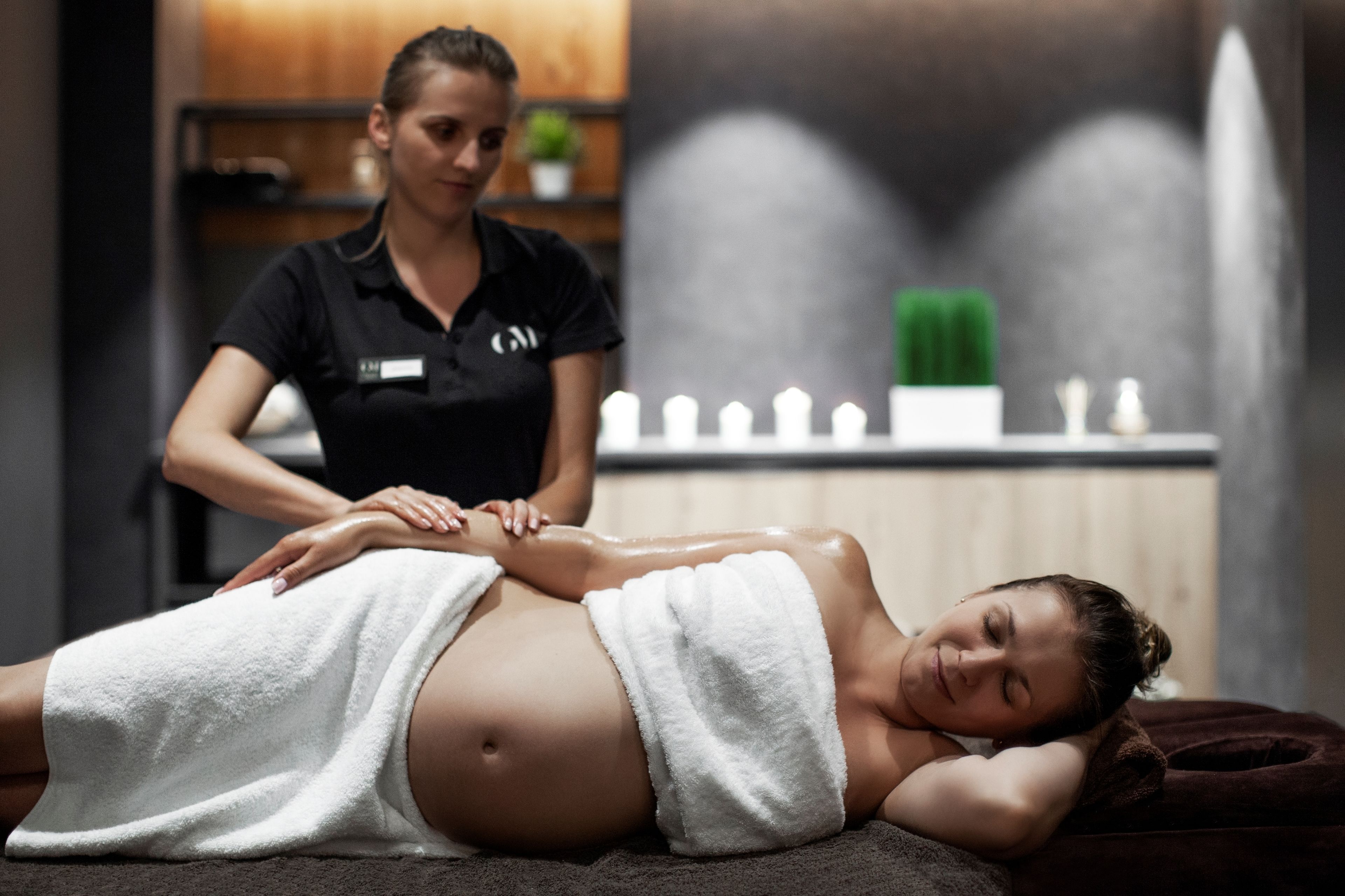 Een persoon ontvangt een rugmassage in een spa, met een massagetafel, een handdoek en een massagetherapeut.