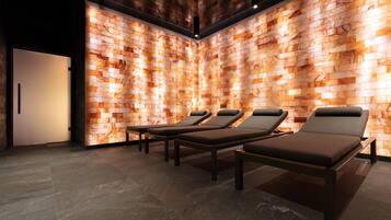 Ein Spa-Raum mit einer Holzvertäfelung, drei Liegen und einer Tür.