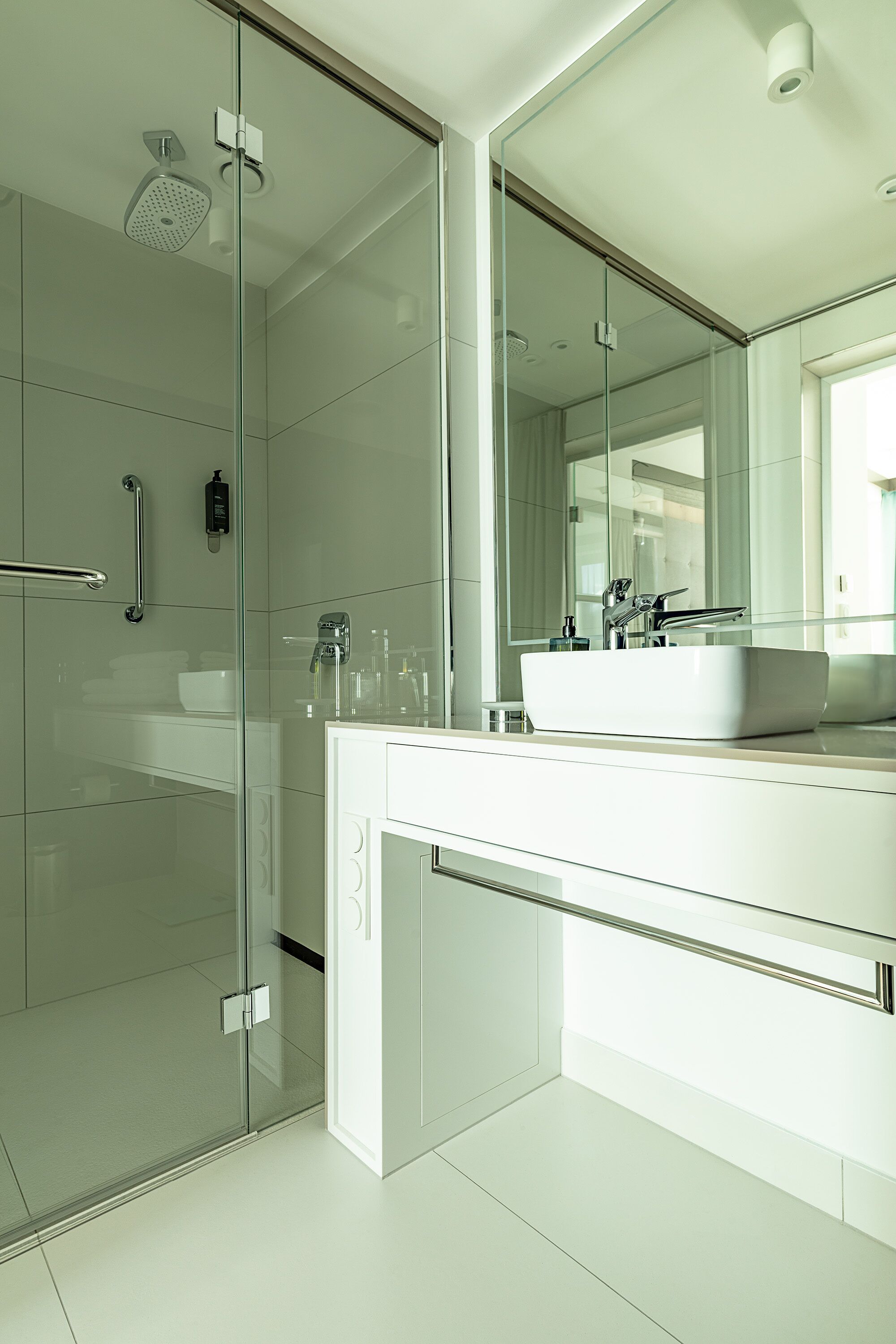 A modern bathroom with a glass-enclosed shower, a white sink, and a large mirror.
