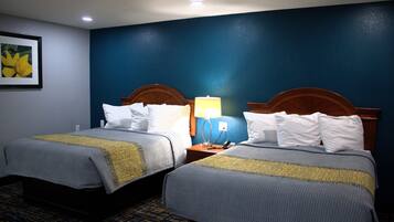 A hotel room with two beds, a nightstand with a lamp, and a framed picture on the wall.