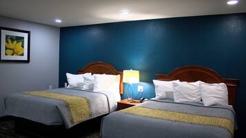 A hotel room with two beds, a nightstand with a lamp, and a framed picture on the wall.