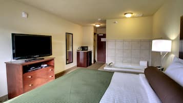 Una habitación de hotel con una cama, un televisor sobre un mueble de madera, un baño con bañera y un espejo en la pared.