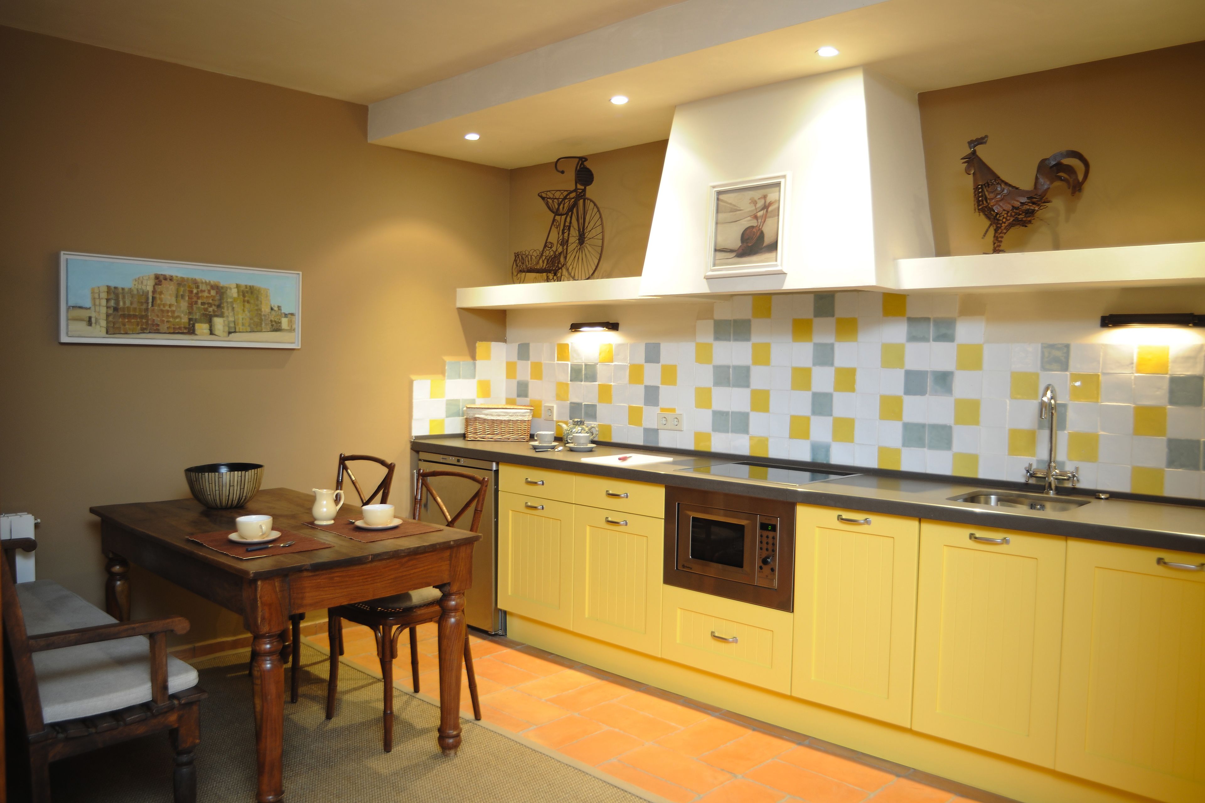 Una cocina con gabinetes amarillos, una mesa de comedor de madera y un salpicadero de azulejos.
