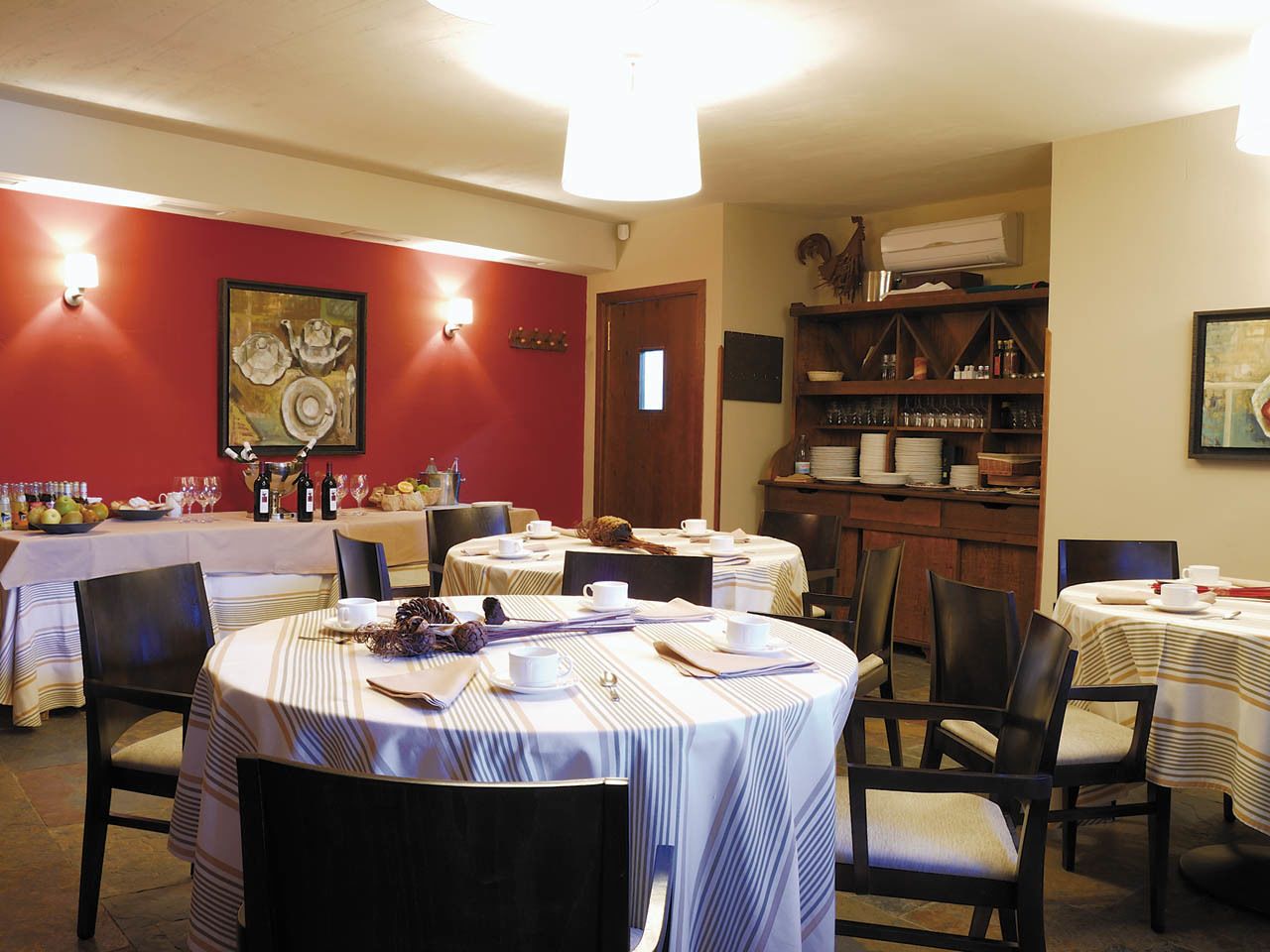A dining area with round tables, chairs, and a buffet setup.