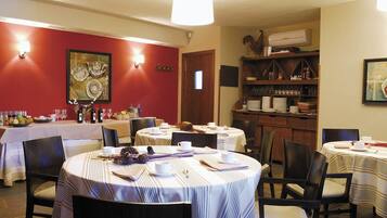 A dining area with round tables, chairs, and a buffet setup.