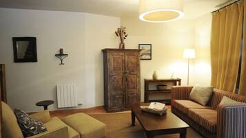 Una sala de estar con sofá, sillón, aparador de madera y una mesa.