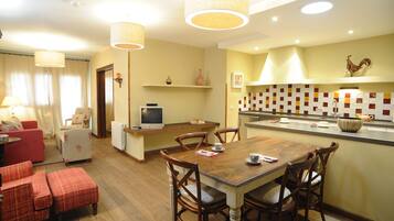 Una sala de estar acogedora con un sofá rojo, una mesa de comedor de madera con cuatro sillas y un televisor sobre un mueble.