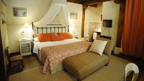 Une chambre à coucher comprenant un lit, des tables de chevet, une commode, un téléviseur et une fenêtre avec des rideaux.