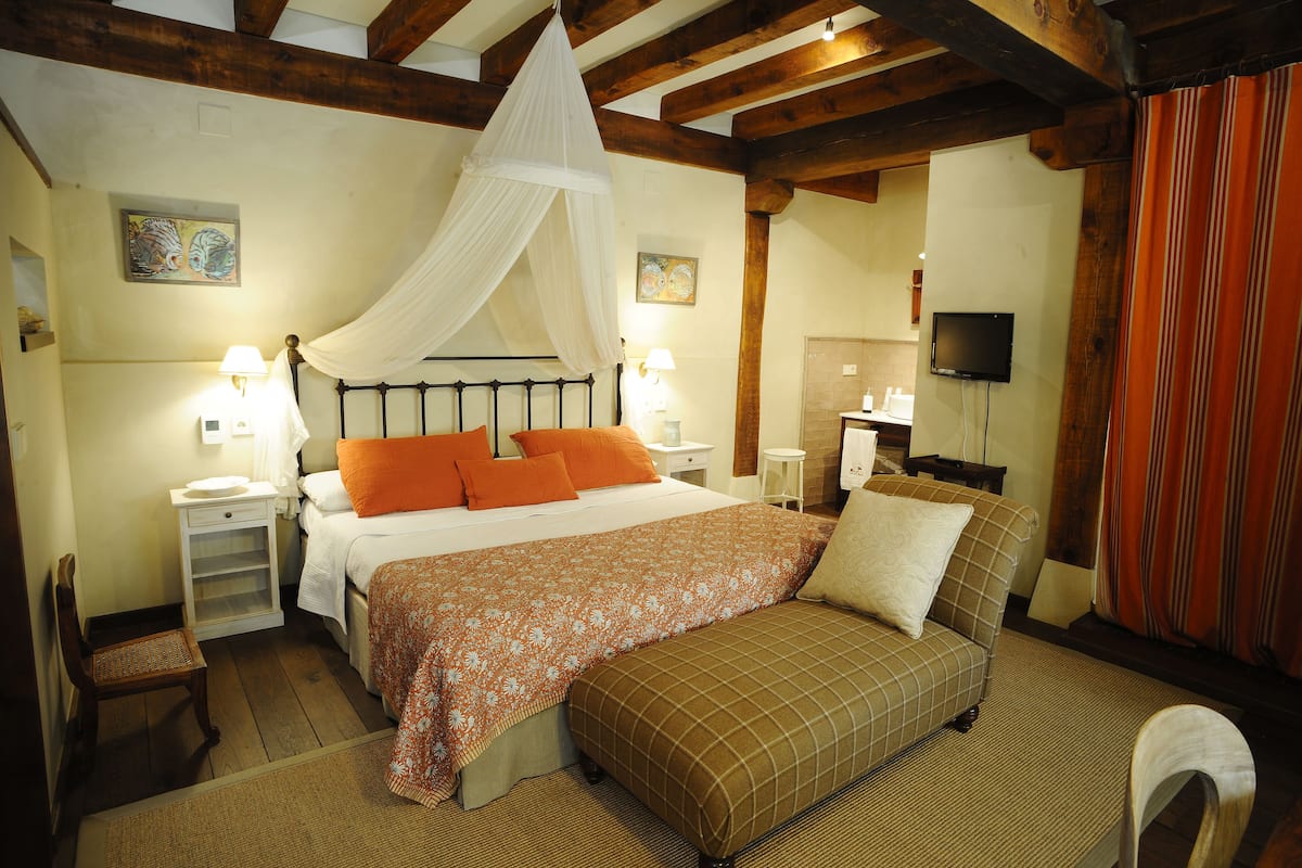 A bedroom with a bed, bedside tables, a nightstand, a television, and a window with curtains.