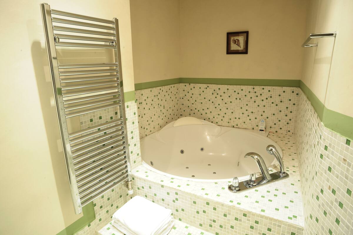 A bathroom with a freestanding bathtub, a towel rack, and a small framed picture on the wall.