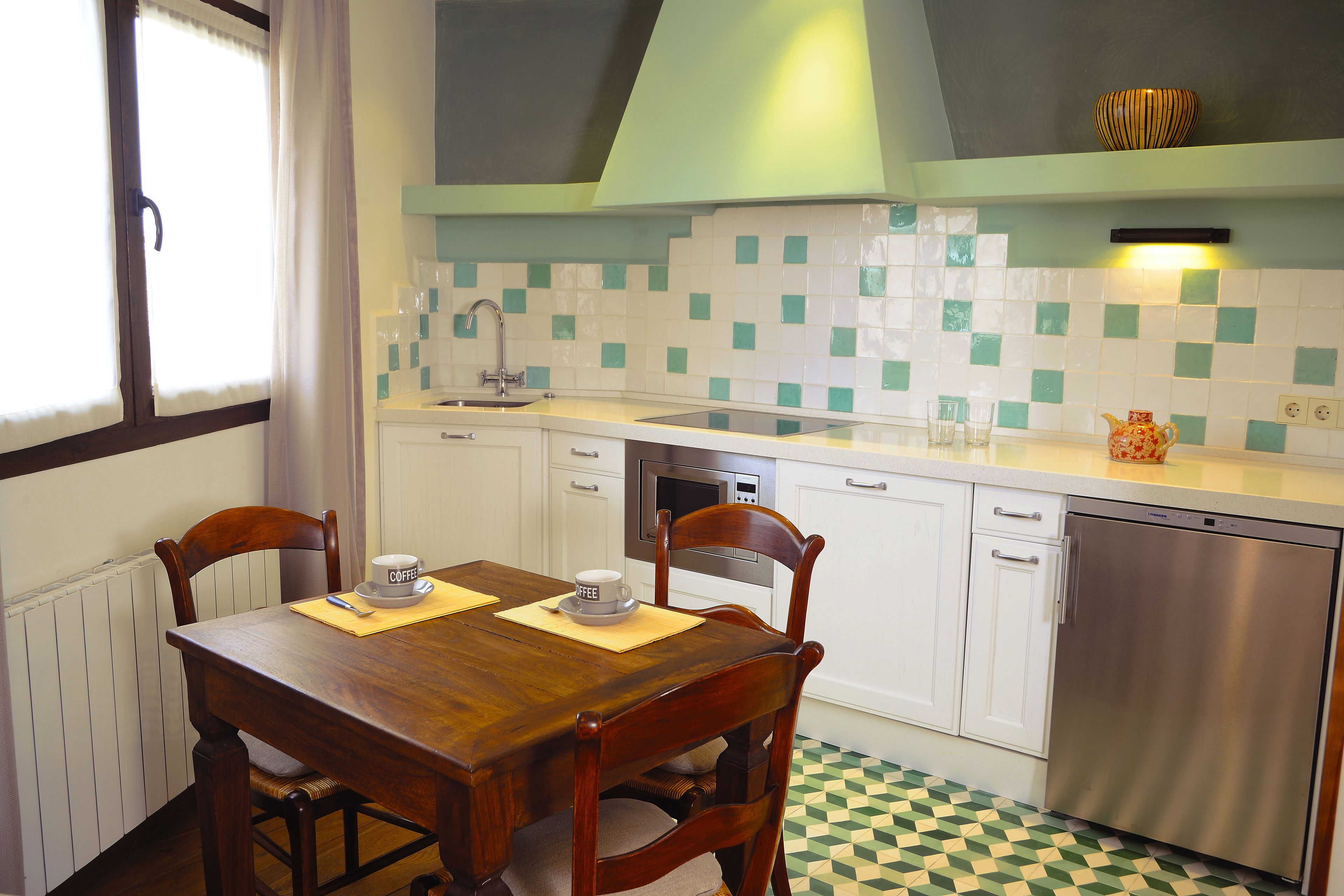 A kitchen with a wooden dining table, chairs, a microwave, and a dishwasher.