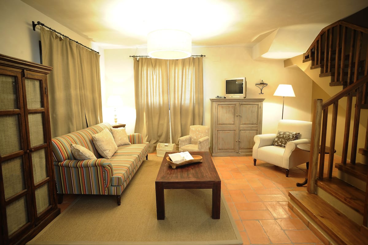 A living room with a sofa, armchair, coffee table, and a television on a cabinet.