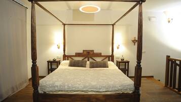 Una cama con dosel, dos mesitas de noche y lámparas fijadas a la pared.