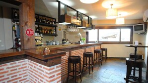 Un espace bar avec un comptoir en briques, des tabourets et des étagères remplies de bouteilles.