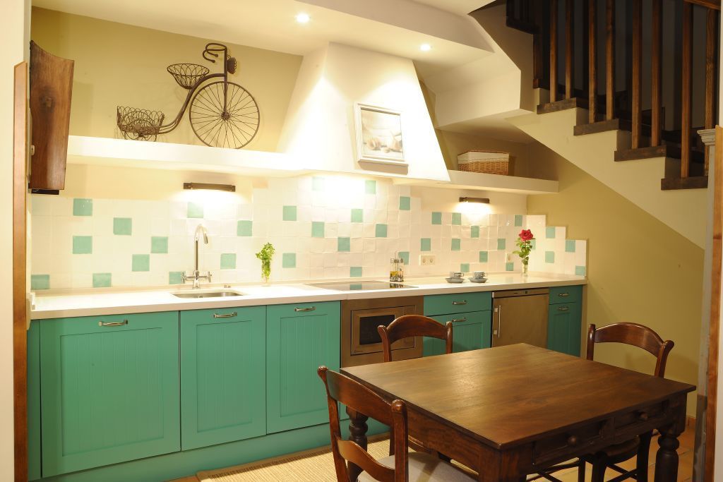 A kitchen with teal cabinets, a wooden dining table, and a bicycle decoration on the wall.