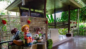 A covered outdoor area with a bamboo fence, a welcome sign, and a bench. - Tara Lake Hotel (Bangkok)