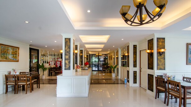 A spacious hotel lobby with a central reception desk, multiple dining areas, and a chandelier. - Tara Lake Hotel (Bangkok)
