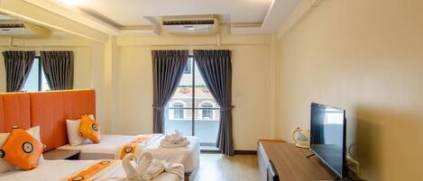 A hotel room with two beds, a TV, a desk with a phone, and a view of buildings through large windows.