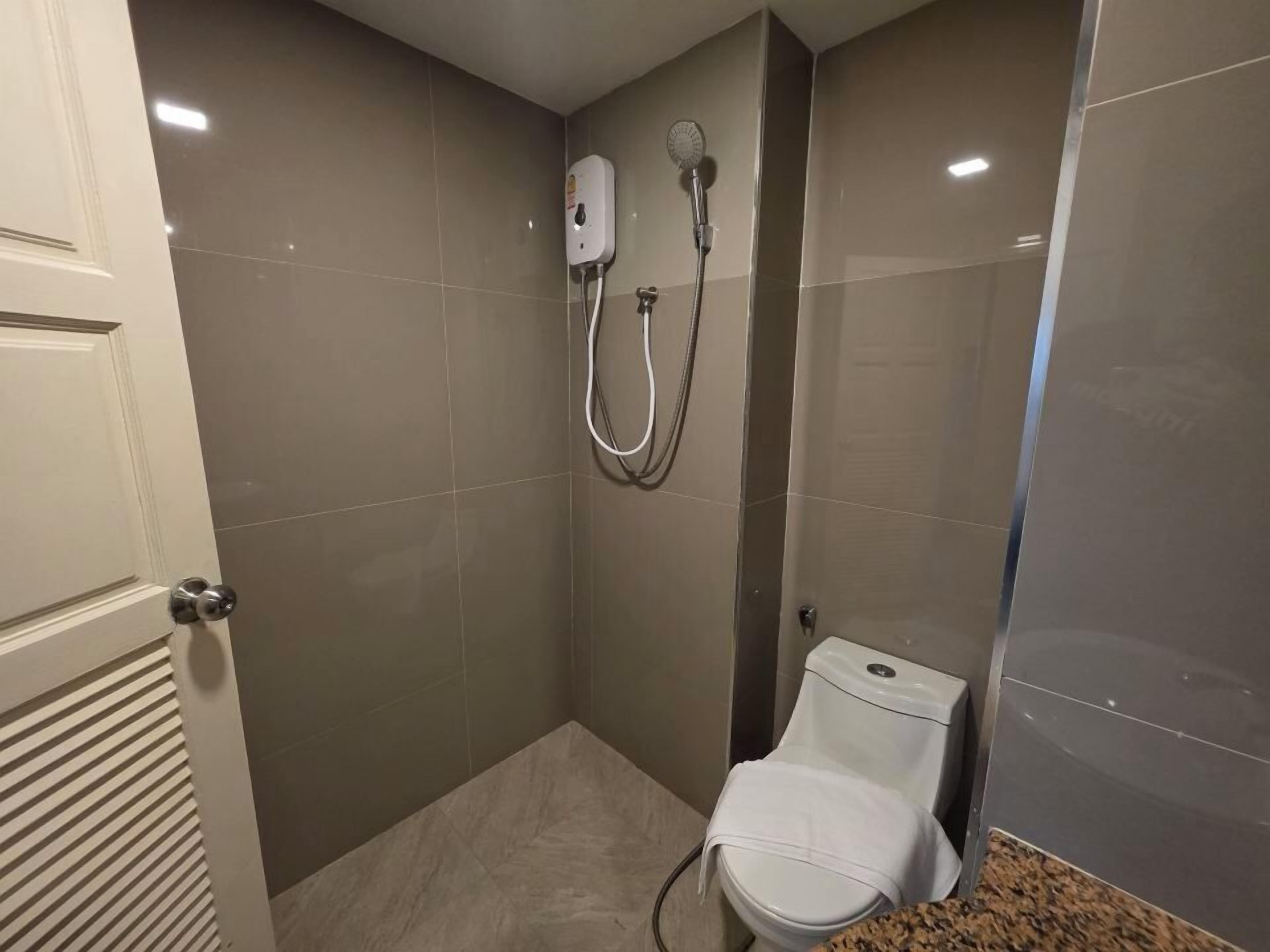 A small bathroom with a toilet, a shower, and a towel rack.