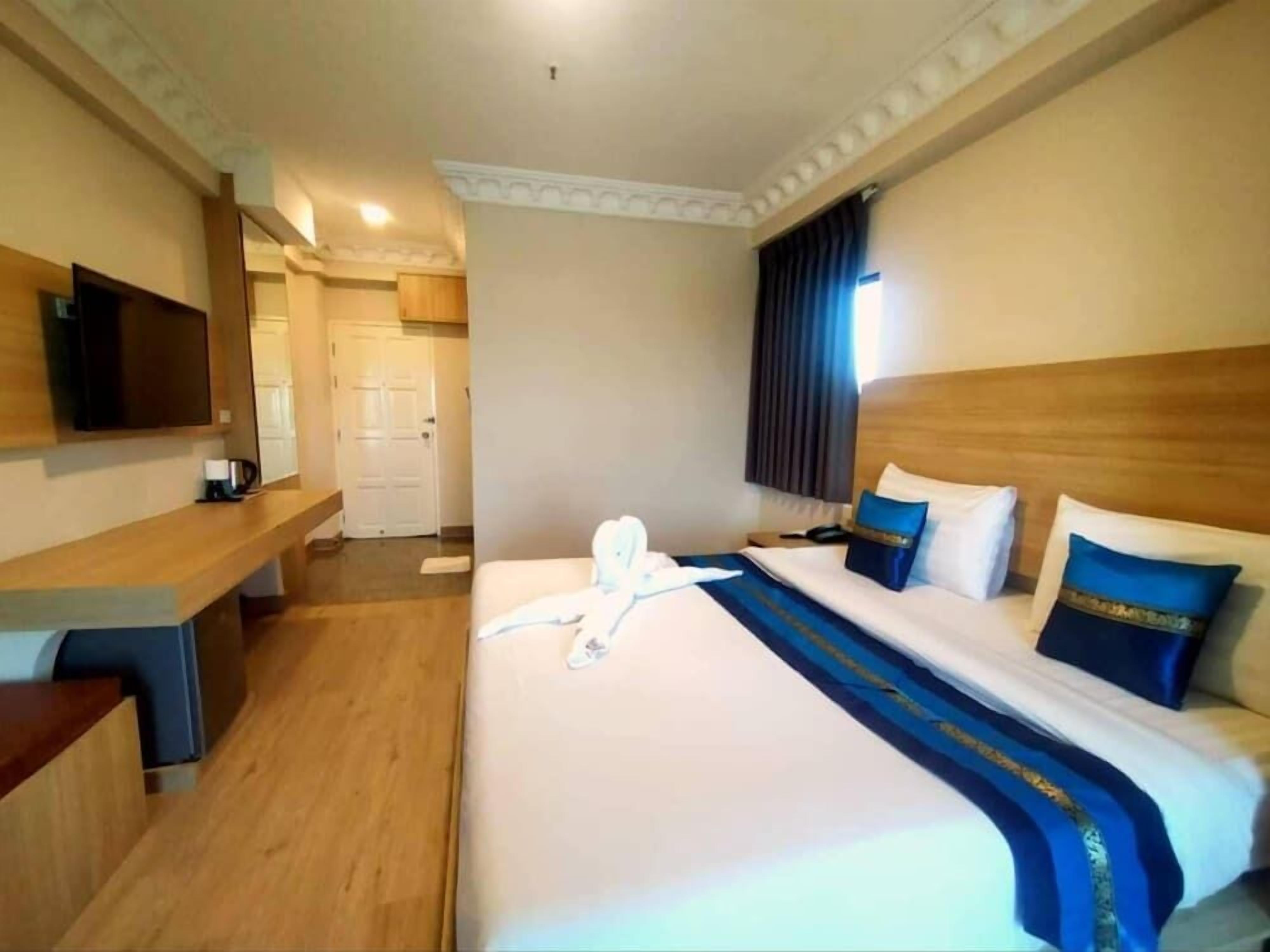 Habitació d'hotel amb un llit, una taula de treball, una televisió i una porta.