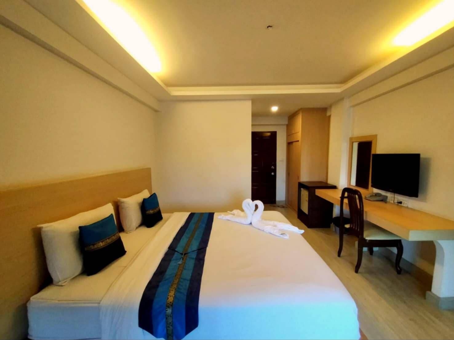 Ein Hotelzimmer mit einem Bett, einem Schreibtisch, einem Stuhl, einem Fernseher und einer Tür.