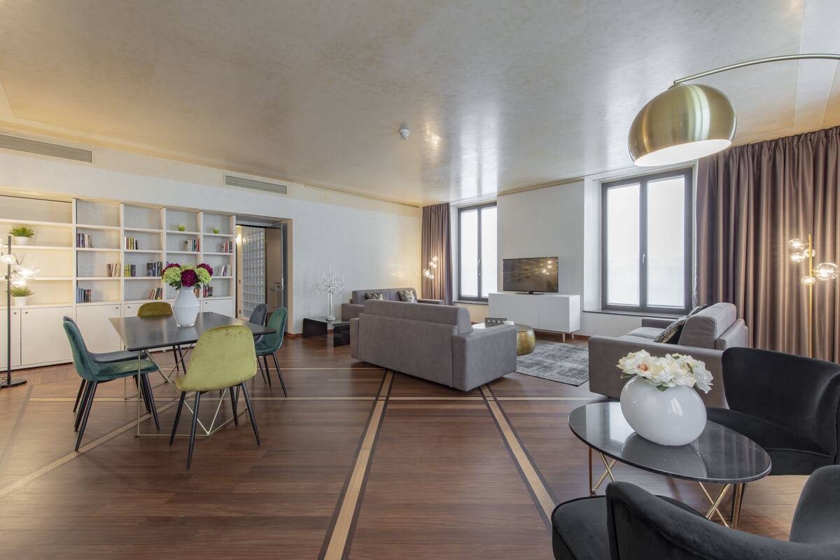 Una sala de estar moderna con comedor, un conjunto de sofás y una estantería.