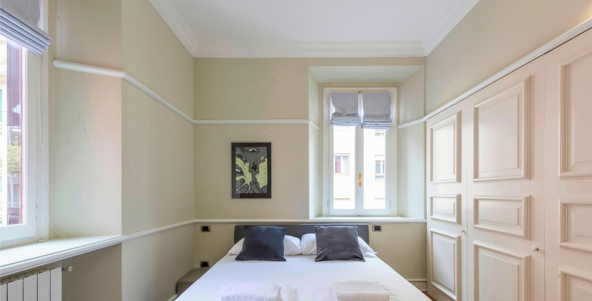 A bedroom with a bed, a window, and a door.