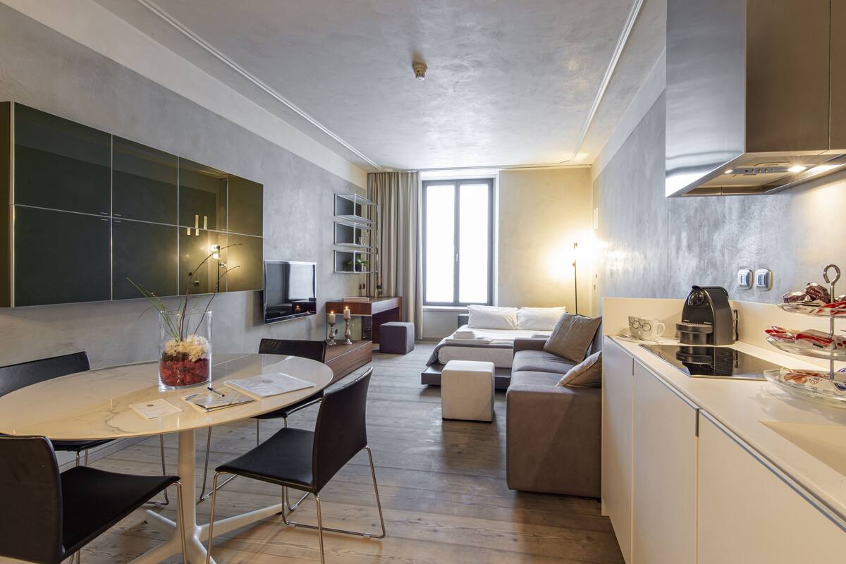 Una cocina moderna con zona de comedor, sofá y cafetera.