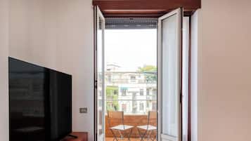 Ein Zimmer mit Fernseher, eine Glasschiebetür zu einem Außenbereich mit Tisch und Stühlen.