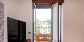 Een kamer met een televisie en een schuifdeur naar een buitenruimte met een tafel en stoelen.