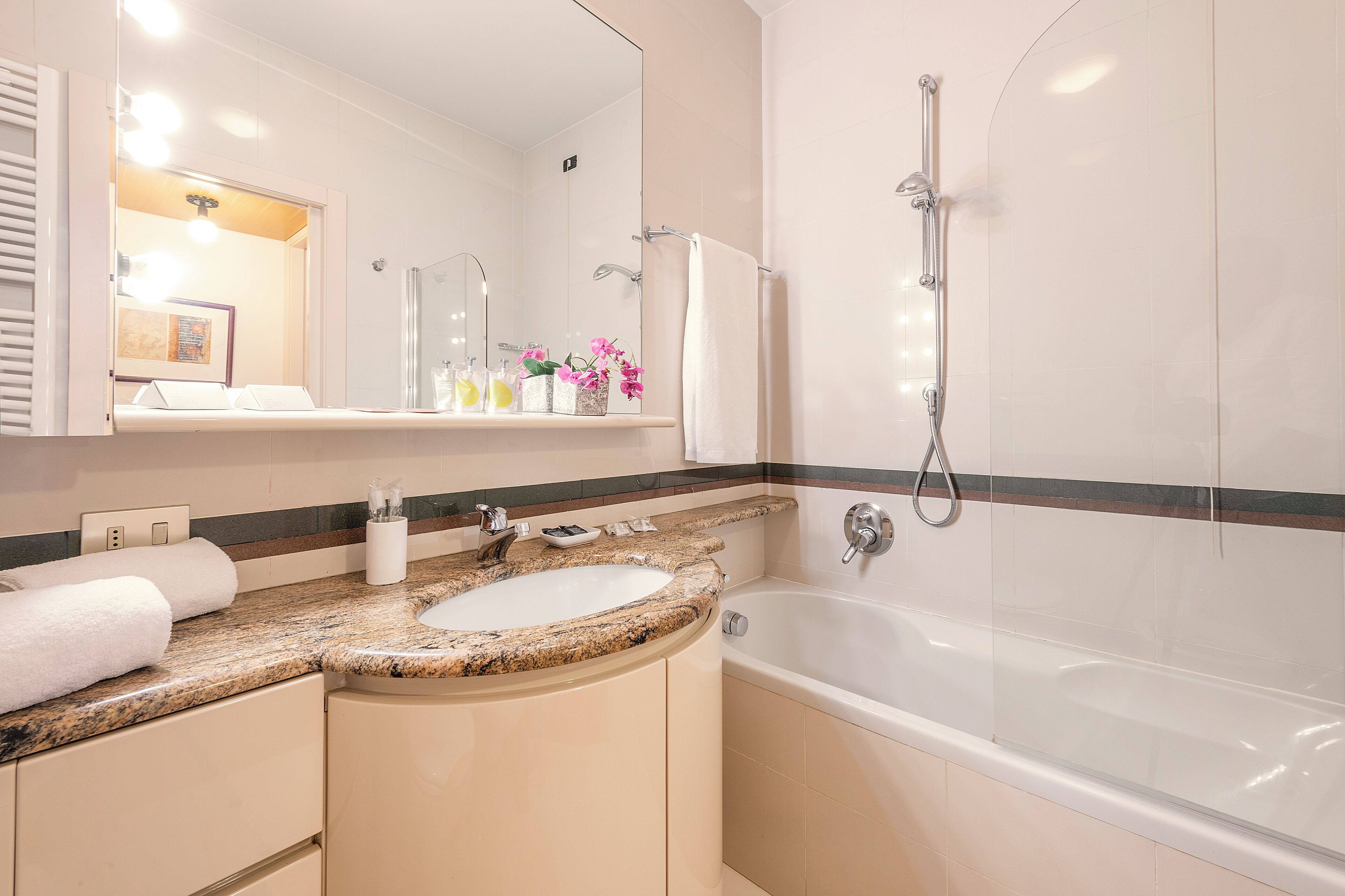 A modern bathroom with a granite countertop sink, a bathtub, and a shower.