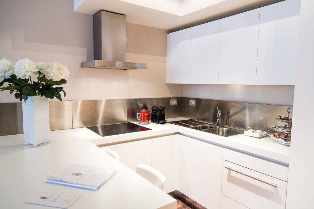 Een moderne keuken met witte kasten, roestvrijstalen apparatuur en een centraal eiland met zitplaatsen.