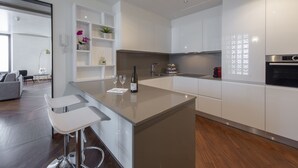 Een moderne keuken met witte kastjes, een centraal eiland met barkrukken en een inbouwoven.