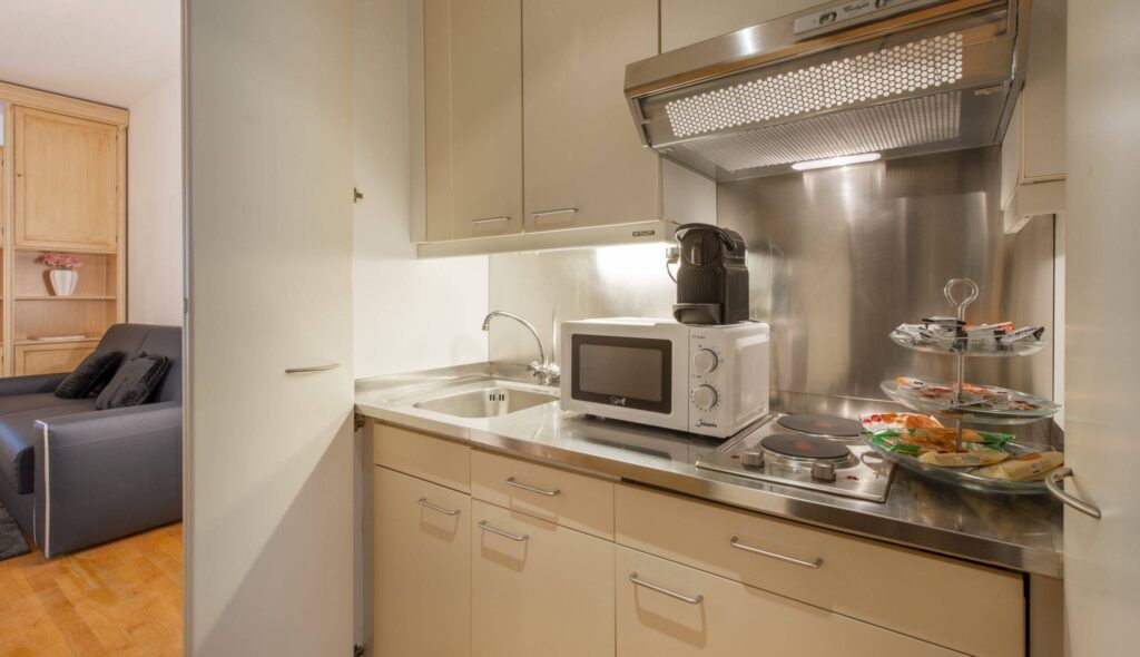 A compact kitchen with a microwave, coffee maker, and a small dining area with a glass display case.