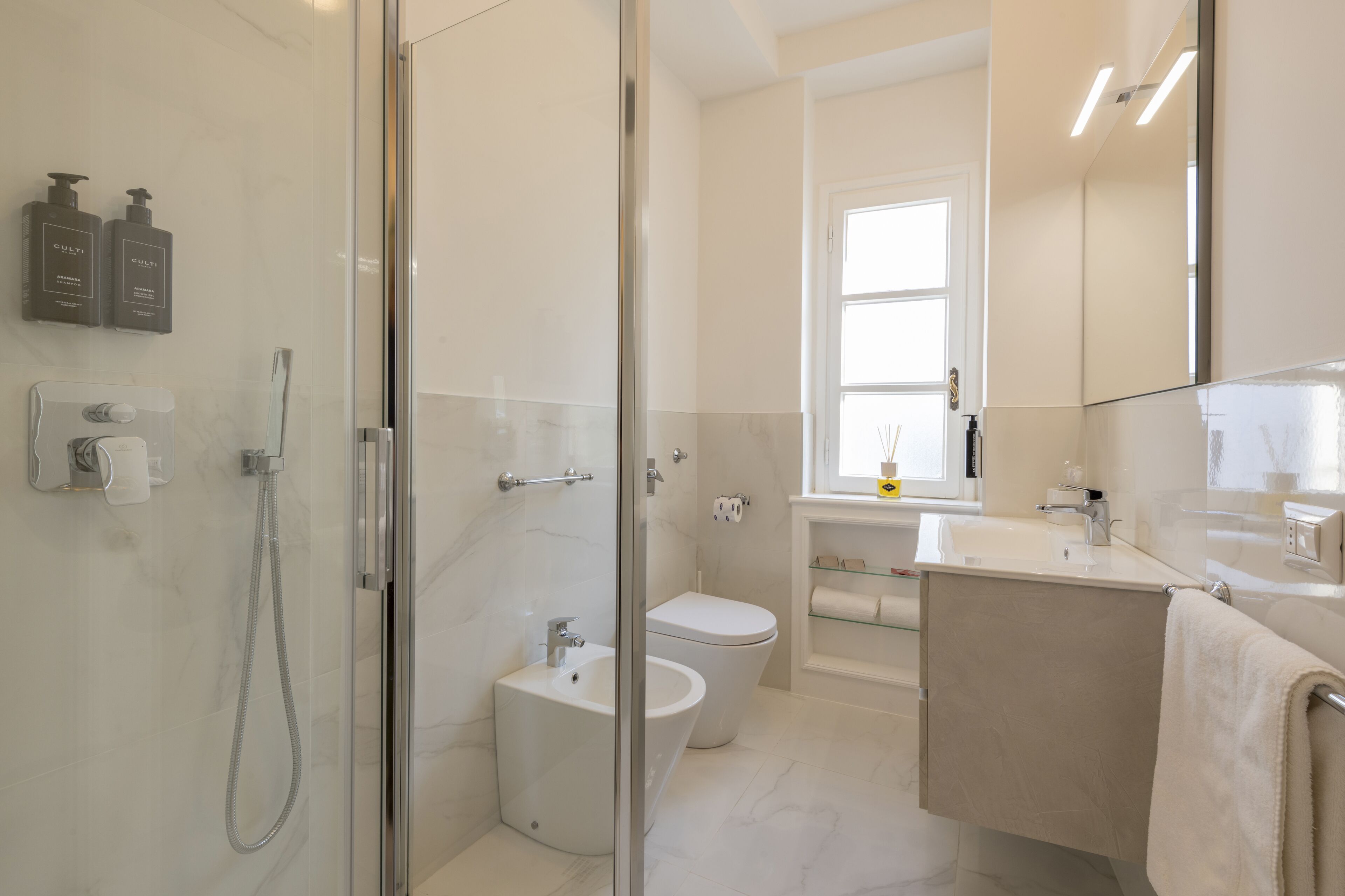 A modern bathroom with a glass shower enclosure, a white toilet, and a vanity with a mirror.