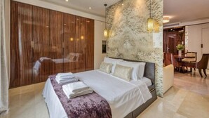 Een moderne slaapkamer met een groot bed, een houten garderobe en een wand bekleed met marmer.