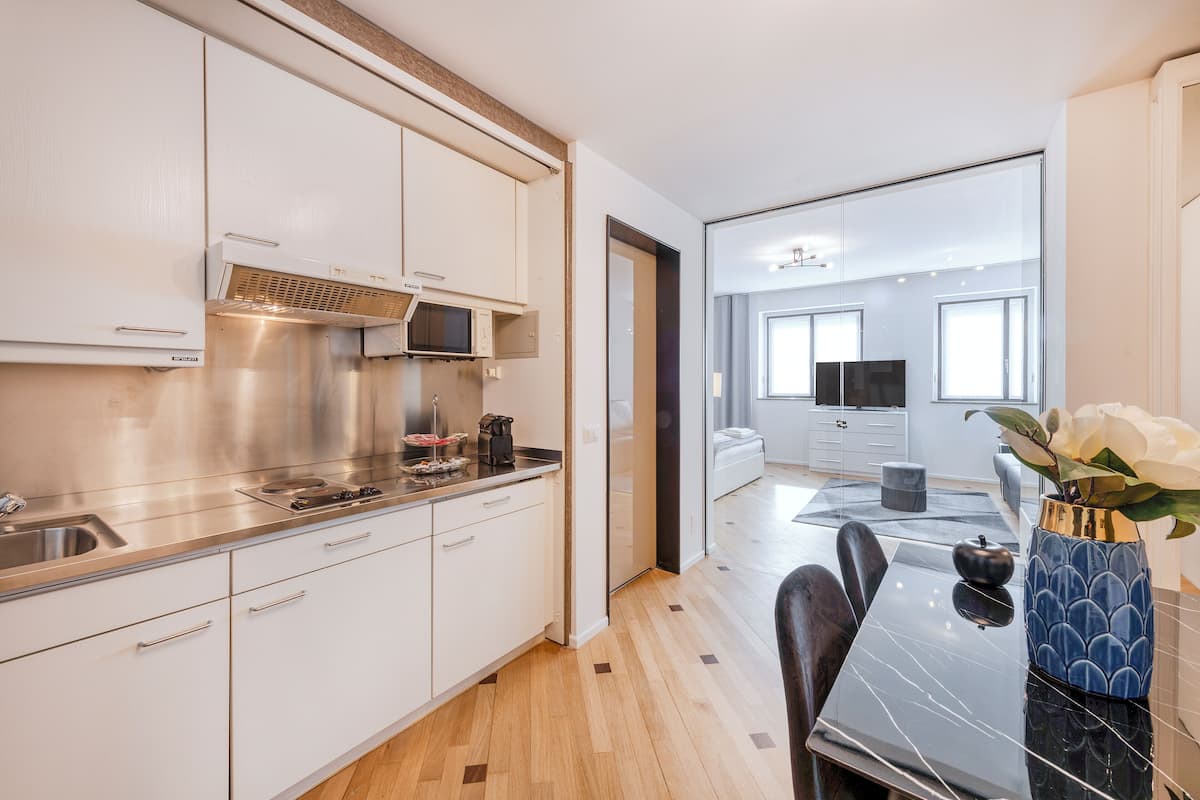 Una cocina moderna con electrodomésticos de acero inoxidable, un comedor con una mesa de mármol negro y vistas al salón.