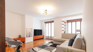 Een moderne woonkamer met een bank, televisie en een houten kast.