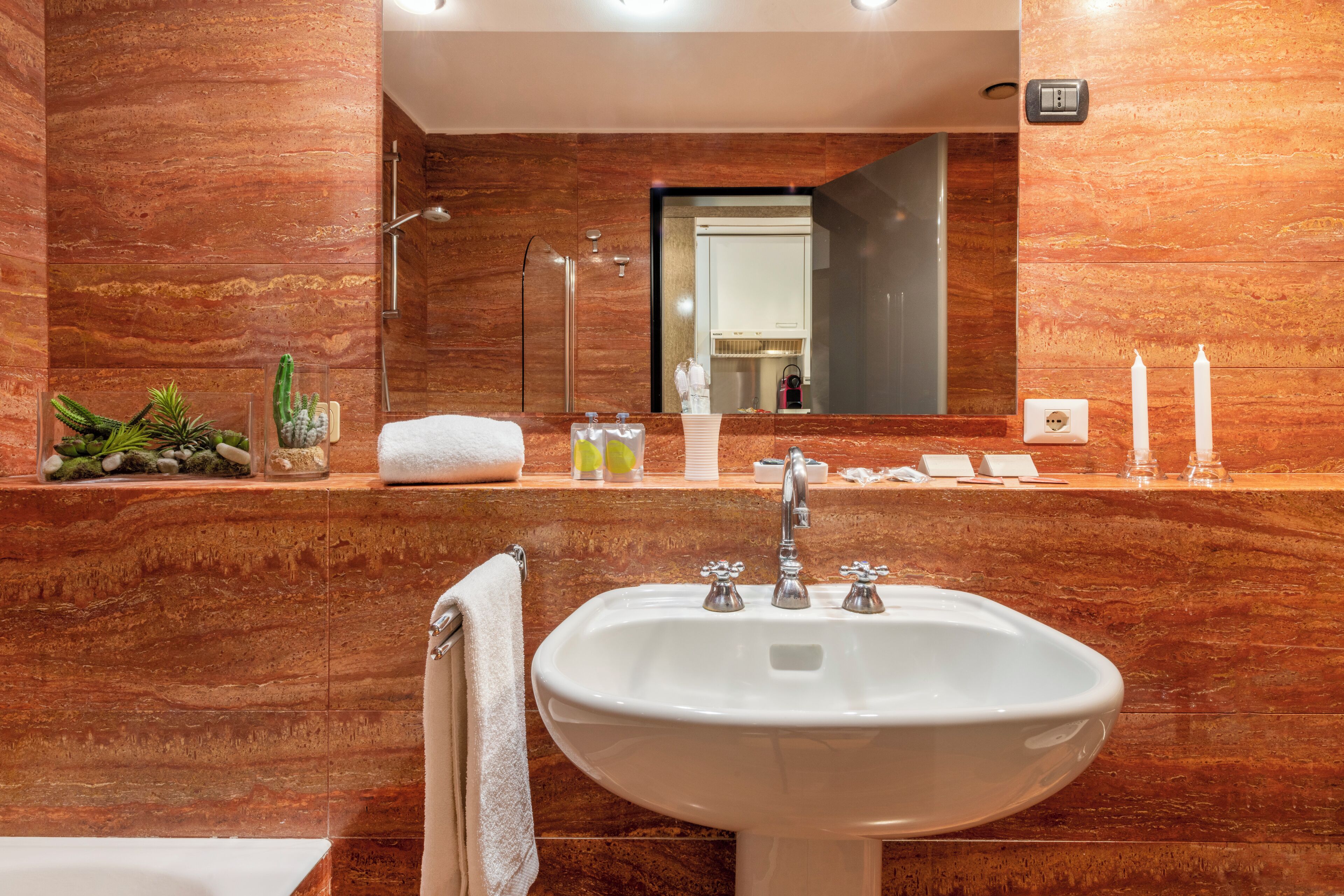 Un baño moderno con lavamanos de mármol, un espejo y una ducha.