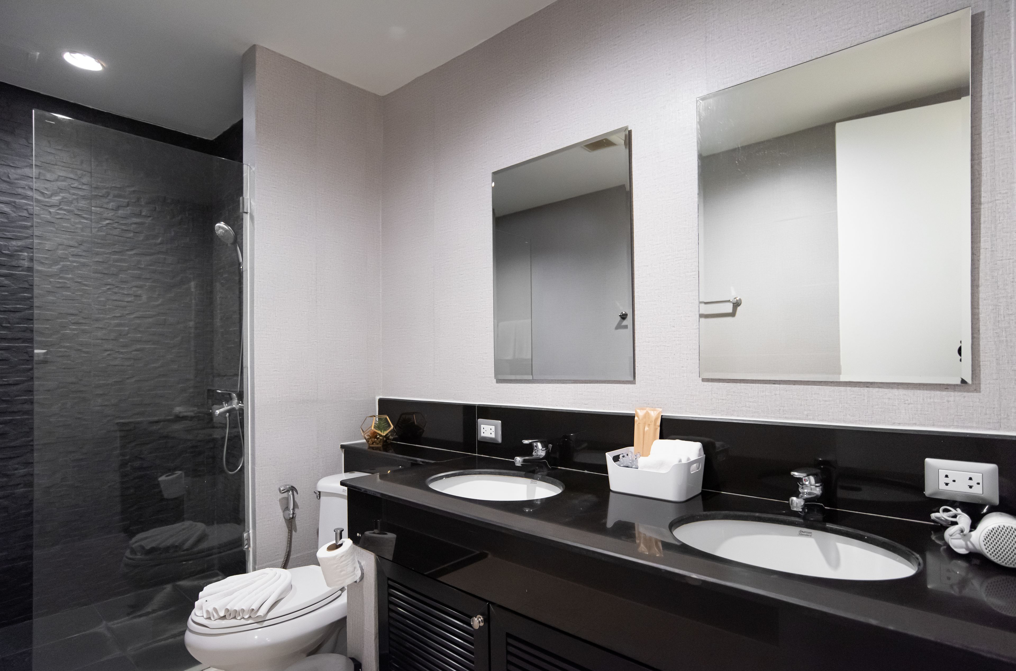 A modern bathroom with a glass shower enclosure, two sinks, and a large mirror above the vanity.