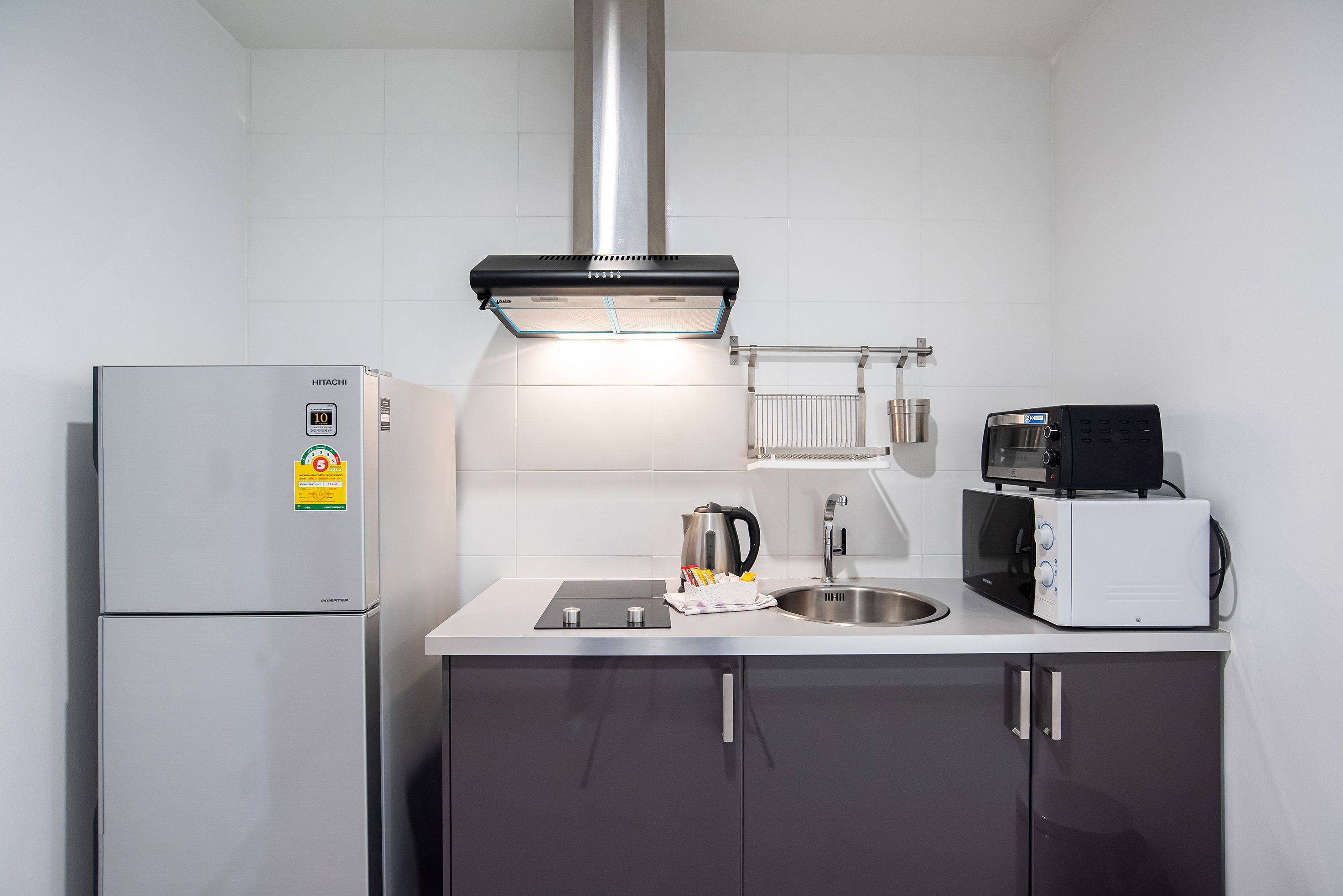 A modern kitchen with a built-in refrigerator, a microwave, a kettle, and a sink.