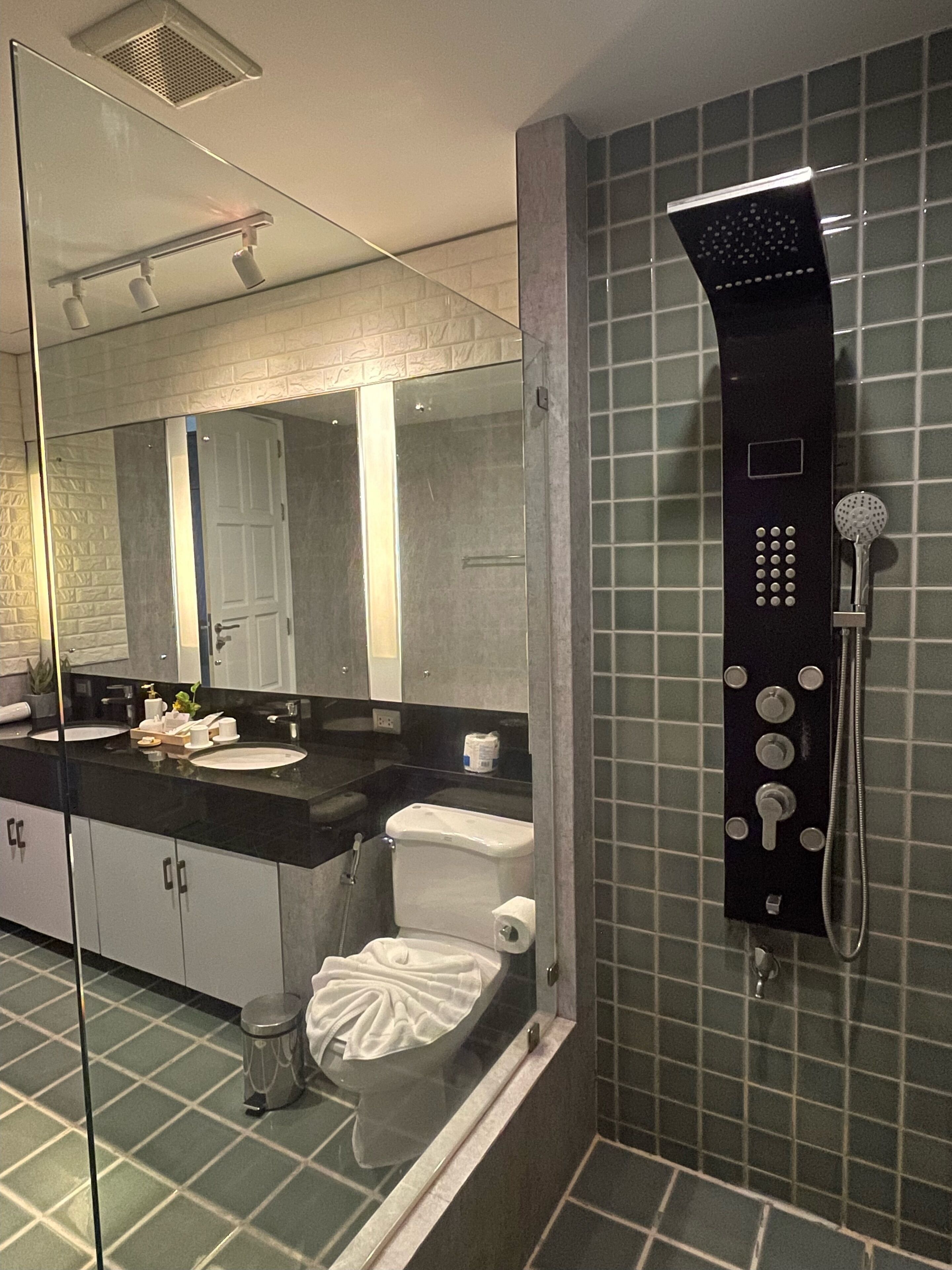 A modern bathroom with a black countertop, a glass shower enclosure, and a toilet with a white lid.