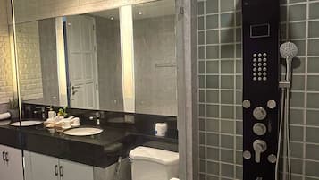 A modern bathroom with a black countertop, a glass shower enclosure, and a toilet with a white lid.