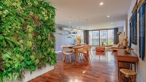 A modern living room with a large green wall, wooden furniture, and large windows. - Benviar Tonson Residence (Bangkok)