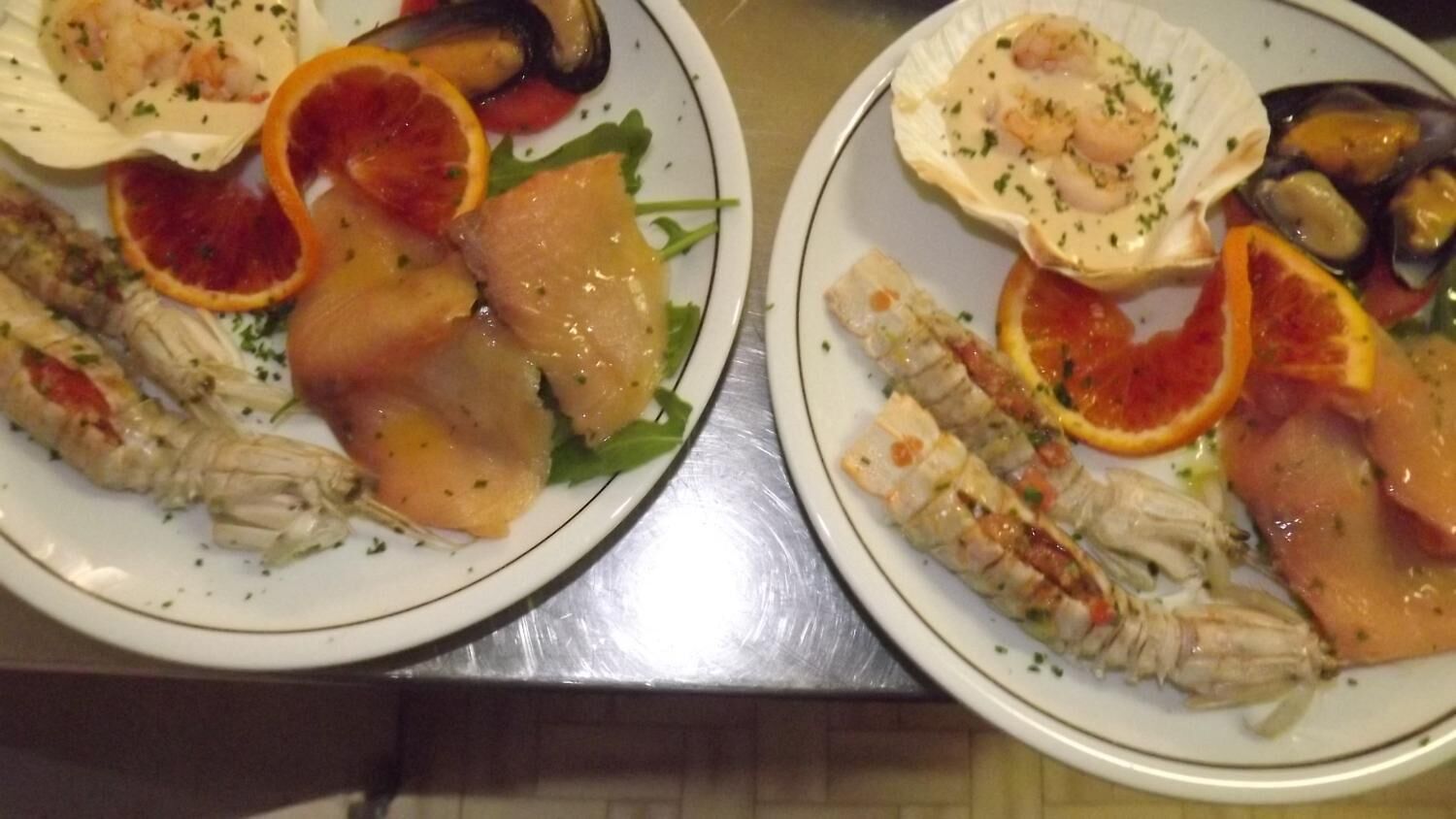 Due piatti di pesce con diversi contorni.