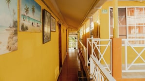 A corridor with yellow walls, a wooden floor, and white railings.