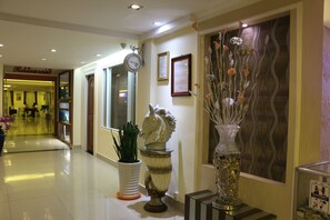 Enter a stylish lobby with polished floors, decorative vases, and a clock.
